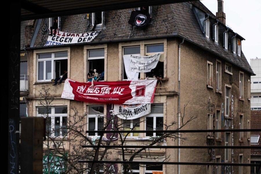 Das Haus in der Gunderrodestraße mit vielen Bannern und Menschen, die in den Fenstern sitzen.