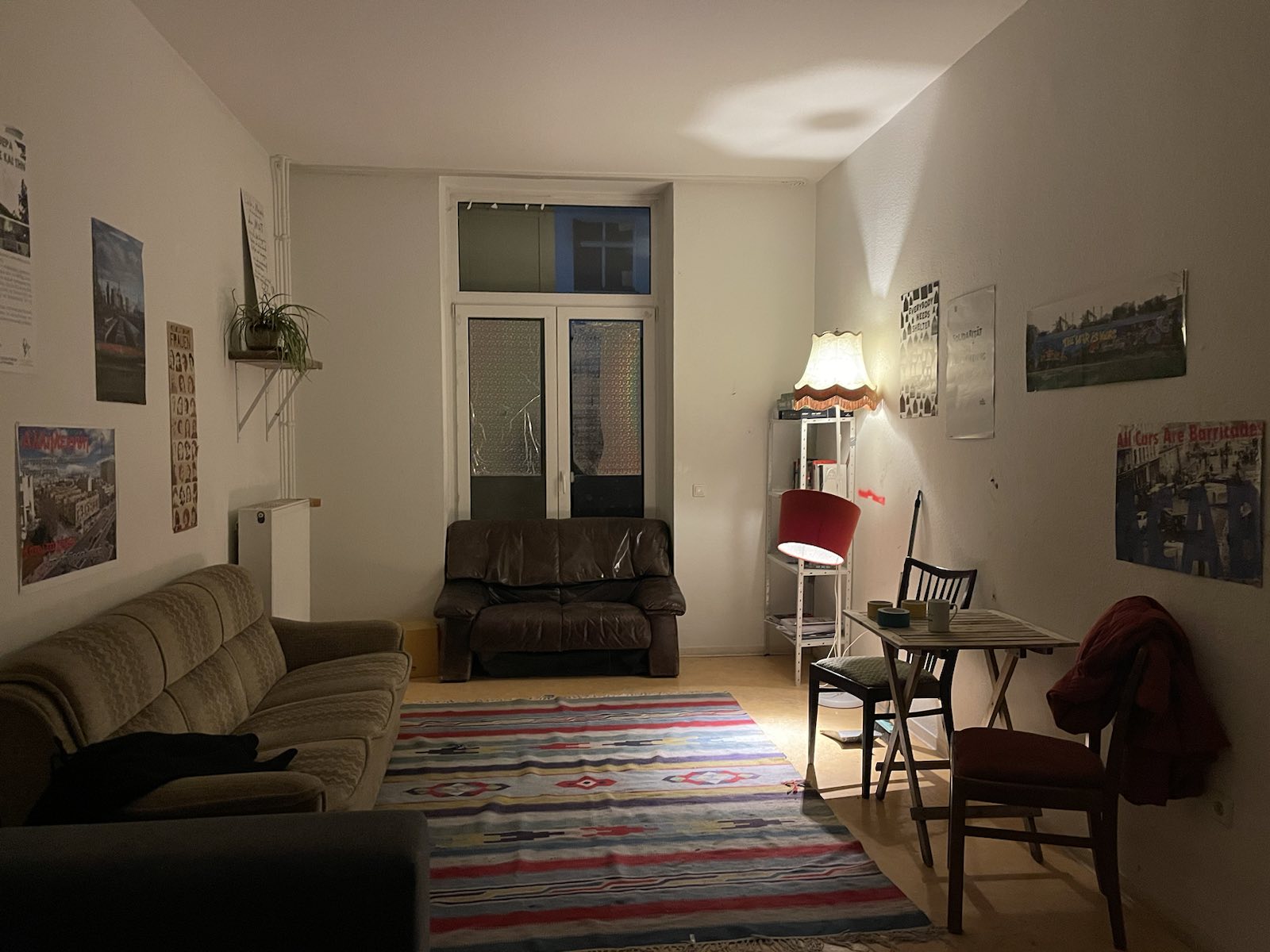 Blick in ein WG-Zimmer, da mit Teppich, Couch und Lampen gemütlich eingerichtet ist.